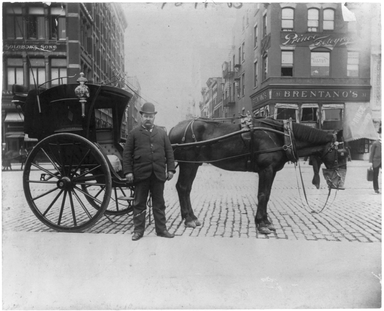 A hansom cab driver standing beside a horse-drawn cab on a city street